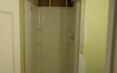 Shower surround installed, you can see the new walls and insulation surrounding it from water damage repairs.